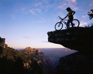 Mountain Biker stood on a ridge at sunrise overlooking the Grand Canyon, Grand Canyon NP, Arizona, USA